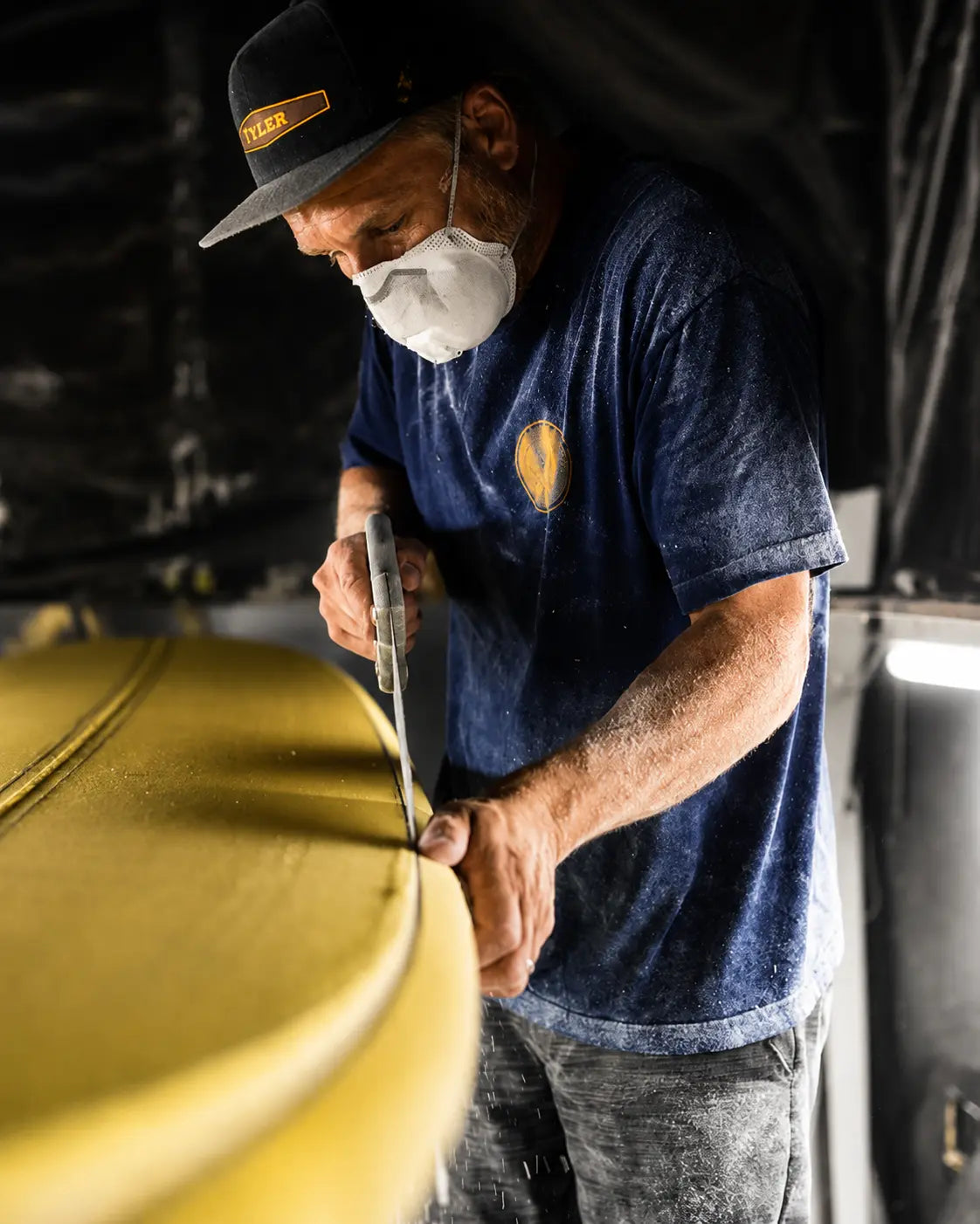 Tyler Hatzikian au rabot sur le rail d'une planche dans son atelier