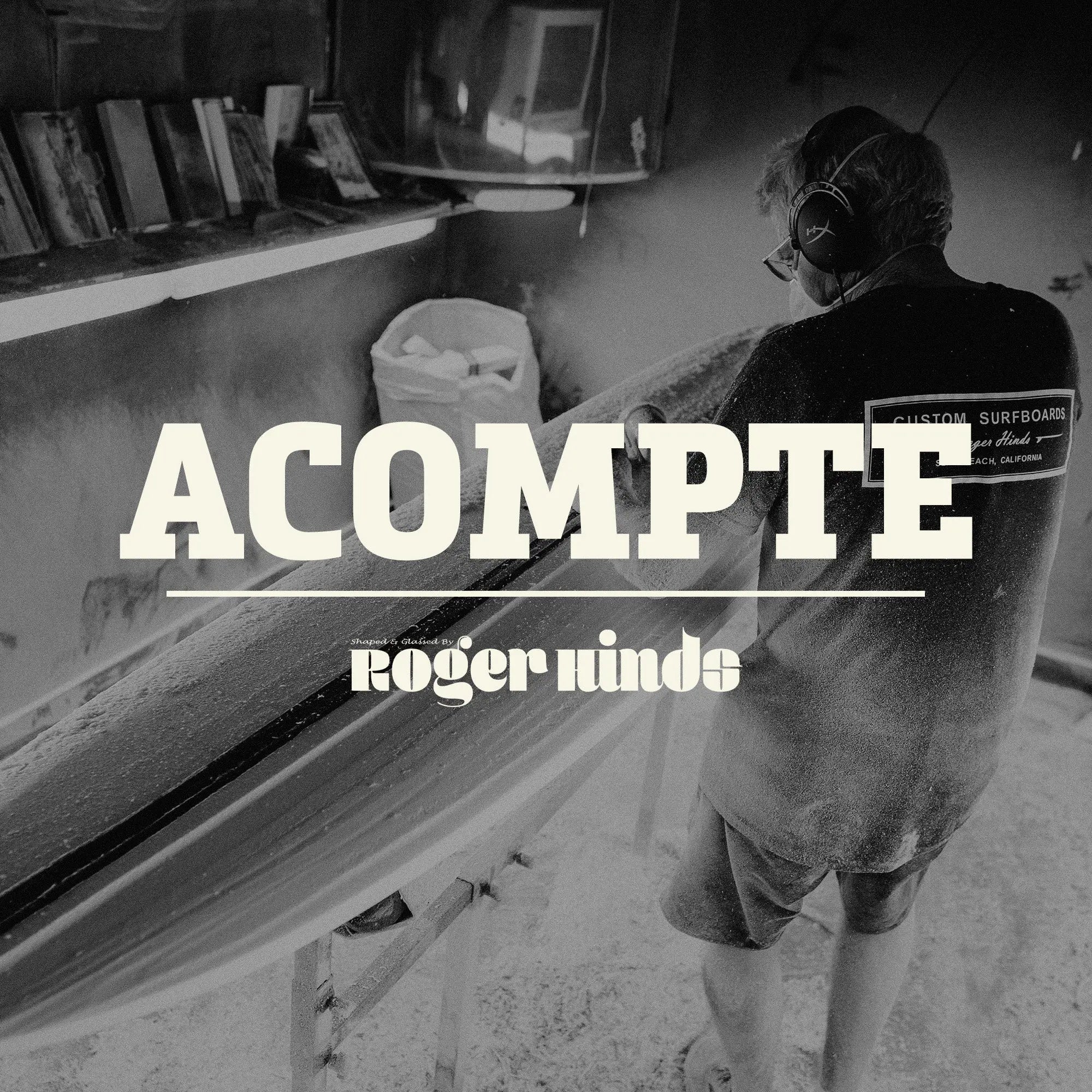 Shapers-Club- Dans un atelier faiblement éclairé, un individu masqué et portant un casque audio façonne minutieusement une planche de surf. Les mots « Acompte deposite - Roger Hinds » sont bien visibles, soulignant le travail artisanal en cours. -surfshop-surfboard