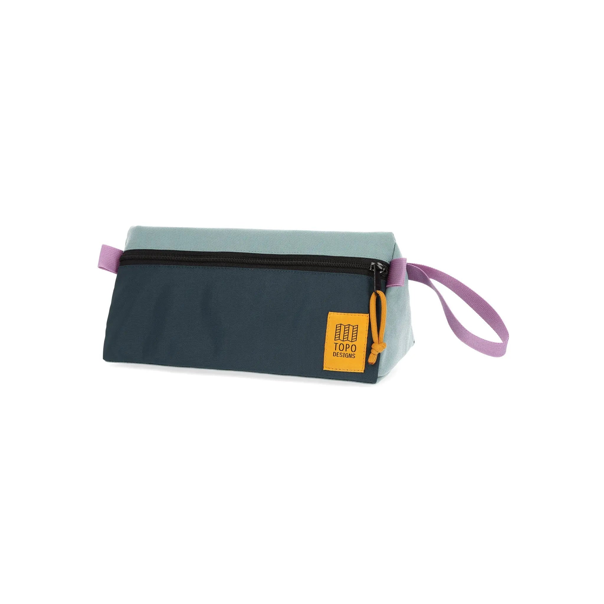 Shapers-Club- La trousse de toilette TOPO en bleu sauge et bleu étang est une élégante pochette rectangulaire zippée avec une palette de couleurs bicolores, présentant une moitié supérieure bleu clair et une moitié inférieure bleu sarcelle foncé. Elle est dotée d'une fermeture éclair noire, d'une poignée en boucle violette et d'un patch carré jaune avec le logo « TOPO » dans un coin. -surfshop-surfboard