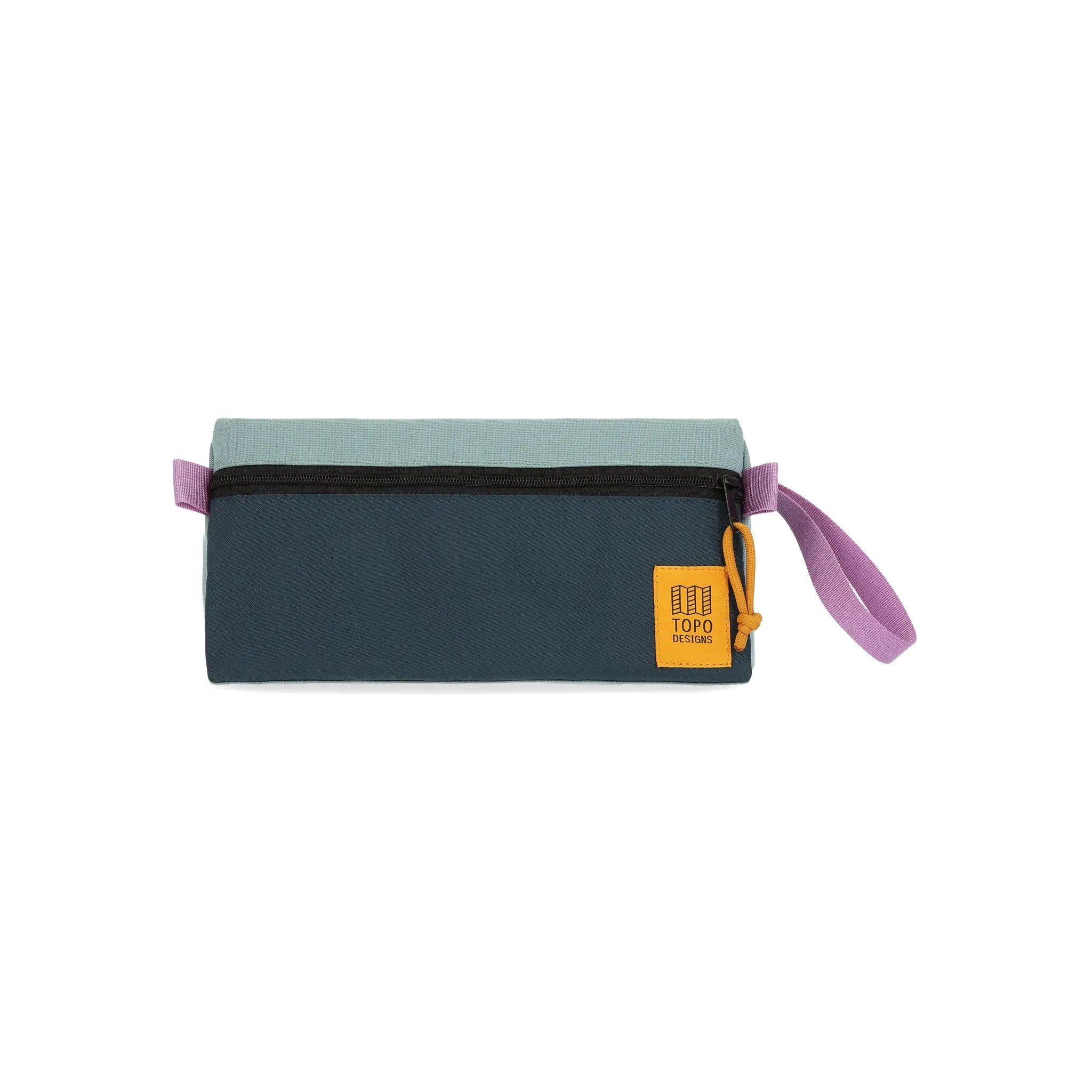 Shapers-Club- La trousse de toilette TOPO présente une forme rectangulaire raffinée avec une fermeture éclair noire et une dragonne rose chic. La moitié supérieure est de couleur vert sauge tandis que la moitié inférieure est bleu étang. Un patch carré jaune avec du texte orne le coin inférieur droit, ajoutant une touche élégante à cet accessoire fonctionnel. -surfshop-surfboard