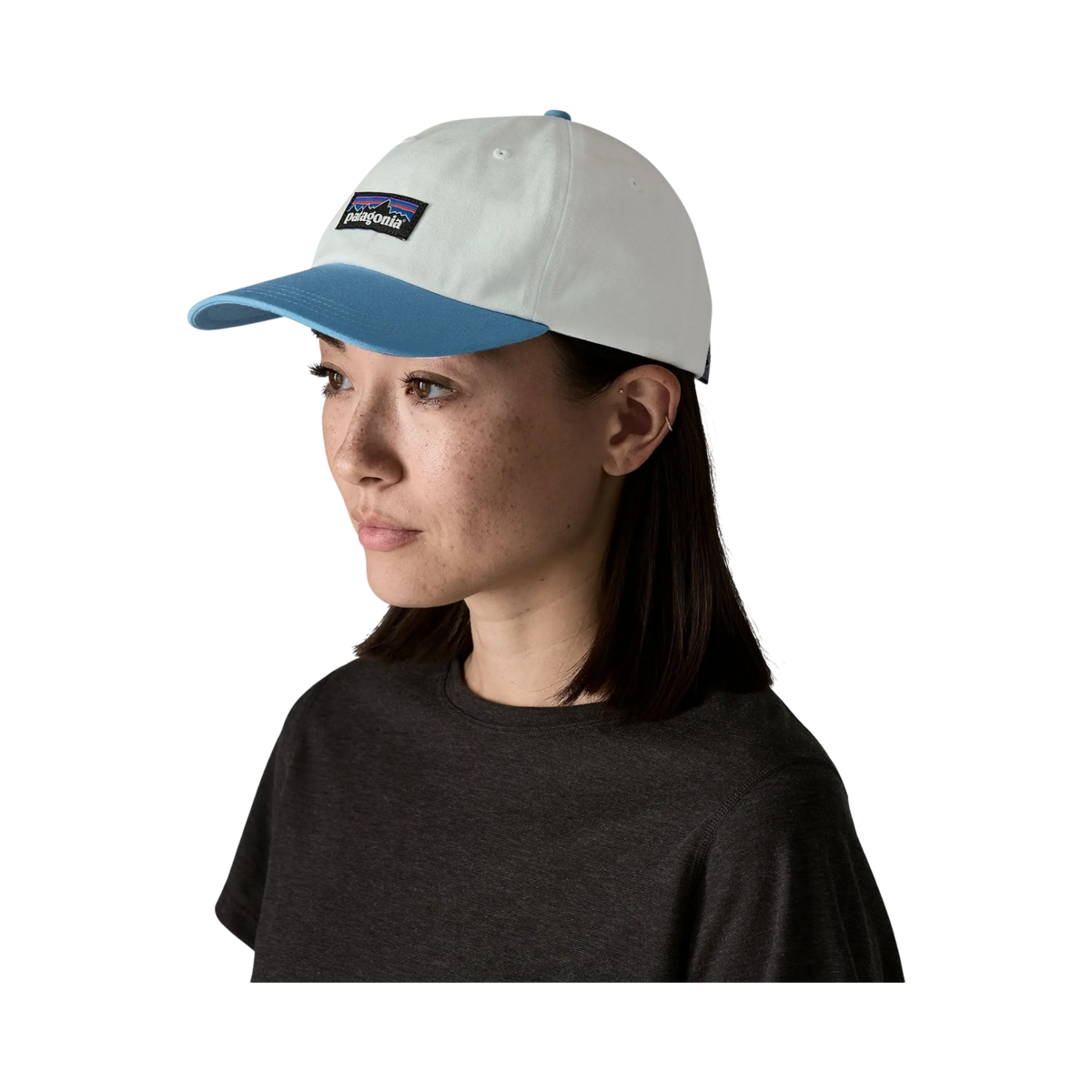 Woman wearing a Surfshop cap - Shapers Club House Patagonia P-6 Label in white and blue on a black background
