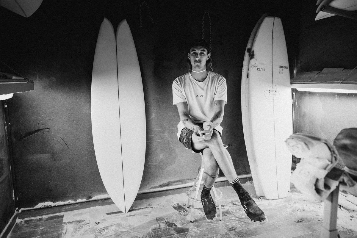 Joshua Keogh dans l'atelier, planches derrière lui