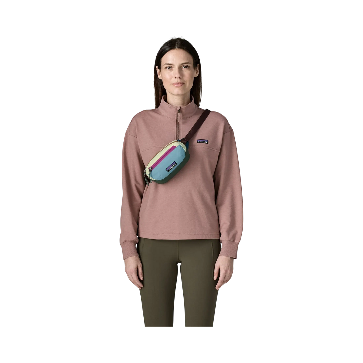 Femme portant le sac banane Patagonia Terravia Mini Hip Pack multicolore en bandoulière sur un pull rose