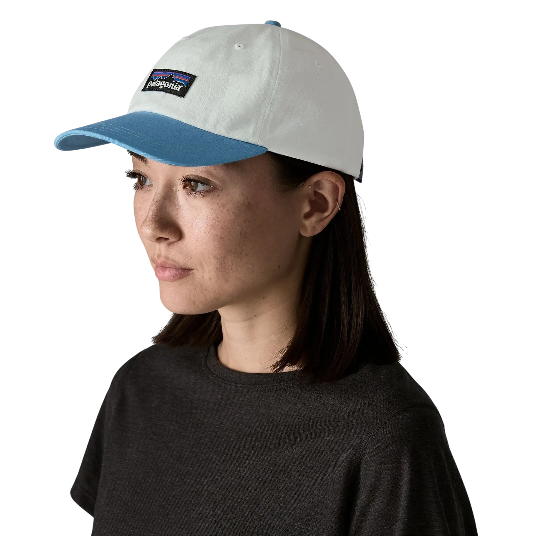 Femme portant une casquette Surfshop - Shapers Club House Patagonia P-6 Label blanche et bleue sur fond noir