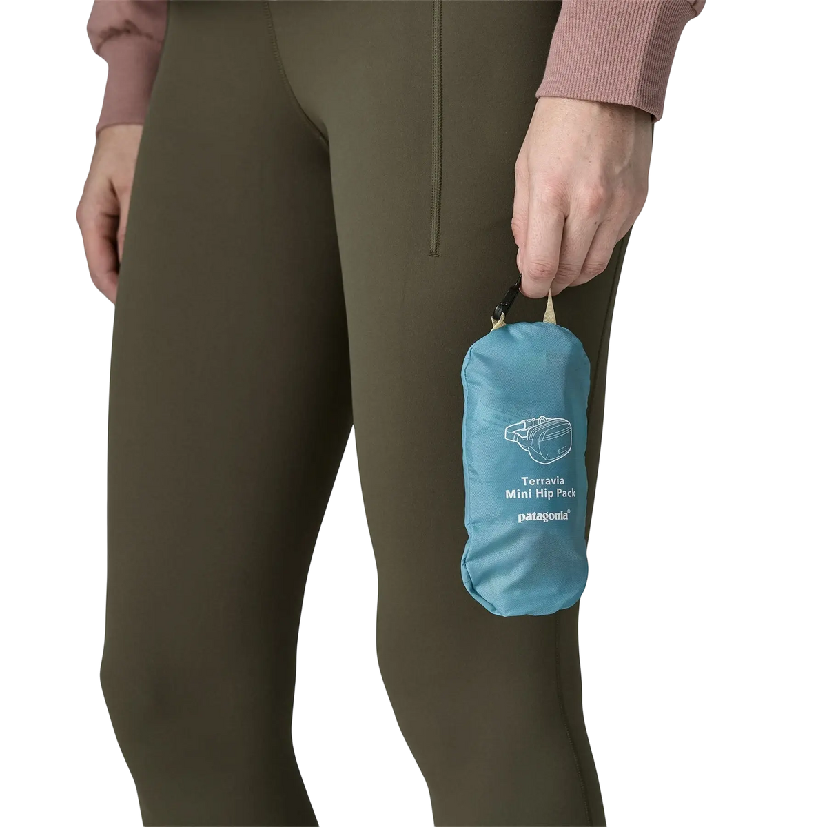 Sac banane bleu Patagonia Terravia Mini Hip Pack tenu à la main par une personne en legging kaki