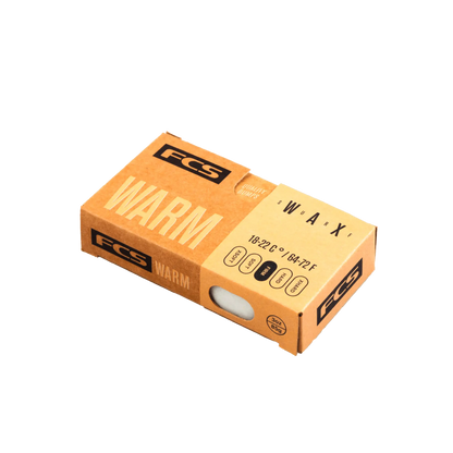 Shapers-Club- Un emballage rectangulaire marron de cire chaude FCS - Wax - Cire pour planche de surf, conçu pour être utilisé dans des eaux dont la température se situe entre 18 et 22 °C (64 à 72 °F). L'emballage comporte une fenêtre qui révèle la cire chaude à l'intérieur et comprend divers détails sur le produit en texte noir. -surfshop-surfboard