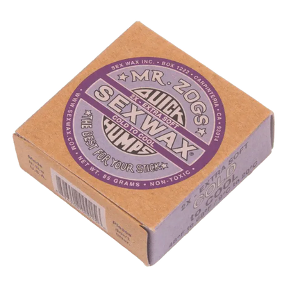 Shapers-Club- Une boîte carrée en carton contenant « Sexwax - Cold » dans une formule extra douce à basse température. La boîte beige comporte des étiquettes violettes et noires avec un texte et une marque clairs. Ce produit non toxique pèse 85 grammes. -surfshop-surfboard