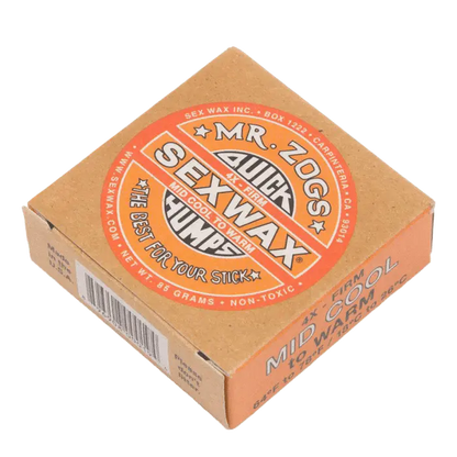 Shapers-Club- L'image présente une boîte orange de 85 g de Sexwax de M. Zog, étiquetée « Quick Humps », « Warm Tropical » et « The Best For Your Stick », conçue pour les planches de surf dans des conditions moyennement fraîches à chaudes. -surfshop-surfboard