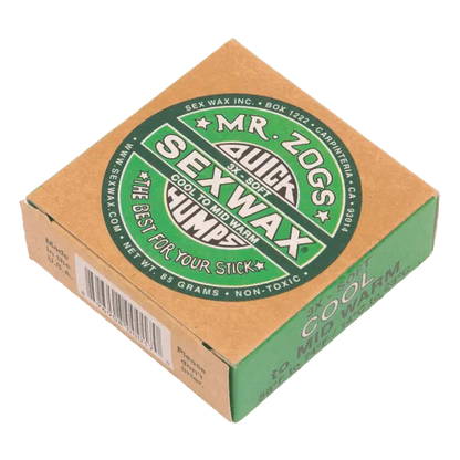 Shapers-Club- Une petite boîte en carton de Sexwax - Cool Surfboard Wax, avec une marque verte et blanche. L'étiquette affiche bien en évidence « Sexwax », « Quick Humps » et « The best for your stick ». La boîte indique qu'elle est conçue pour les températures fraîches à moyennement chaudes, qu'elle a une texture douce et qu'elle pèse 85 grammes. -surfshop-surfboard