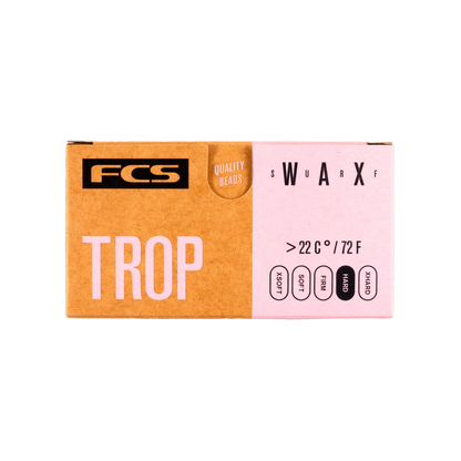 Shapers-Club- La boîte en carton FCS - Wax - Trop présente un design bicolore avec du marron à gauche et du rose à droite. Les textes « FCS », « Wax TROP » et « QUALITY BEADS » sont bien en évidence. Elle indique une plage de température de ">22°C / 72°F" et comprend des options pour différentes conditions telles que "FROID", "FRAIS", "CHAUD" et "TROPICAL". -surfshop-surfboard