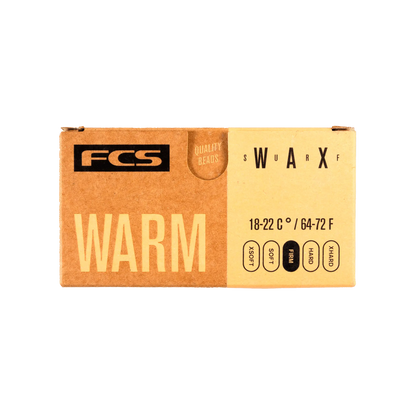 Shapers-Club- La boîte en carton rectangulaire FCS - Wax - Warm affiche bien en évidence le nom de la marque « FCS » dans le coin supérieur gauche et le mot « WARM » en grosses lettres. Elle répertorie les plages de température de 18 à 22 °C / 64 à 72 °F ainsi que les options pour les perles « SOFT », « MED » et « HARD », tout en mettant l'accent sur leurs perles de cire de haute qualité. -surfshop-surfboard