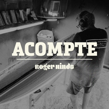 Shapers-Club- Dans un atelier poussiéreux, un individu masqué et portant un cache-oreilles façonne méticuleusement une planche de surf. Le nom « Acompte deposite - Roger Hinds » est affiché bien en évidence, suggérant un dépôt à venir. Des étagères remplies d'outils et une poubelle complètent cette scène minutieuse. -surfshop-surfboard