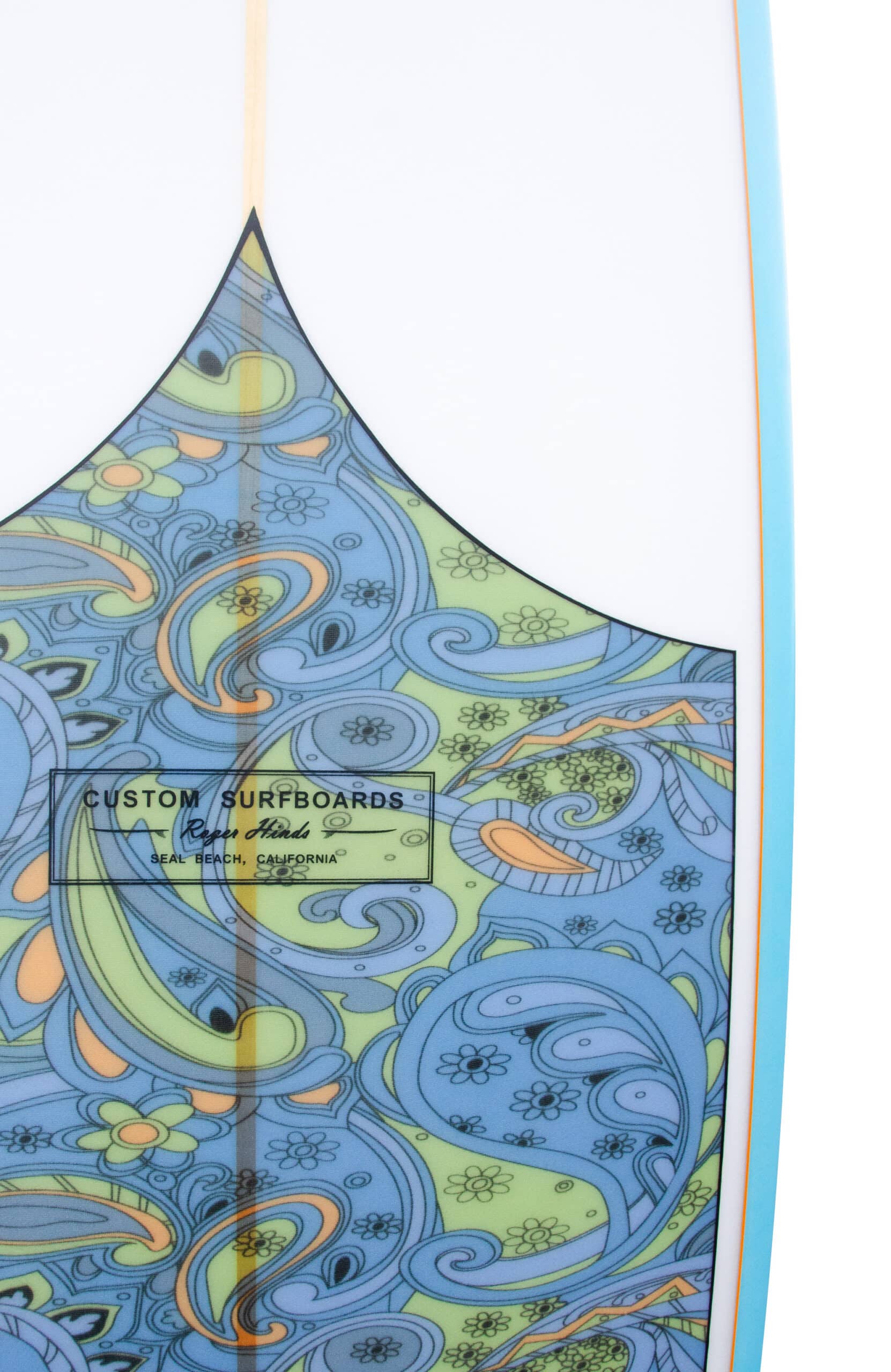 Shapers-Club- Une vue rapprochée de la planche de surf Roger Hinds - Tamago 7'6" x 22" x 2' 7/8" présente un motif abstrait et coloré dans des teintes bleues, vertes et jaunes. Le design complexe présente des éléments en forme de vagues et floraux. Une étiquette sur la planche de surf indique « Custom Surfboards ». -surfshop-surfboard