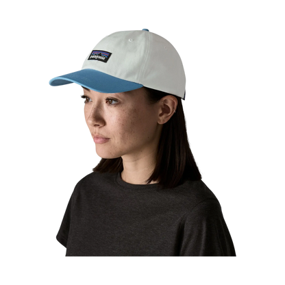 Woman wearing a Surfshop cap - Shapers Club House Patagonia P-6 Label in white and blue on a black background