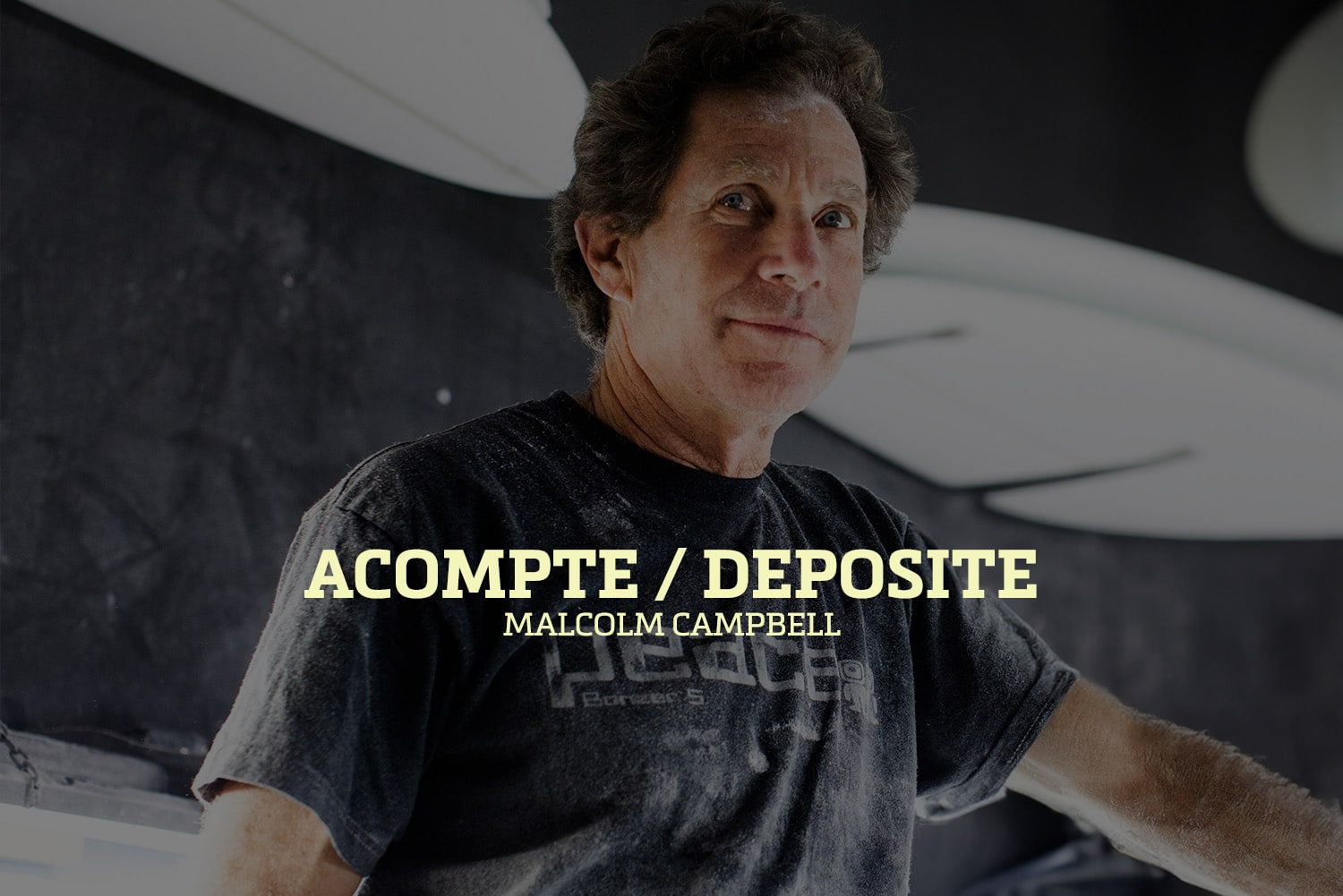 Shapers-Club- Dans une pièce faiblement éclairée, une personne en t-shirt sombre regarde la caméra. Les mots « Acompte deposite - Campbell Brothers » ressortent bien, évoquant l'héritage légendaire des frères Campbell. -surfshop-surfboard