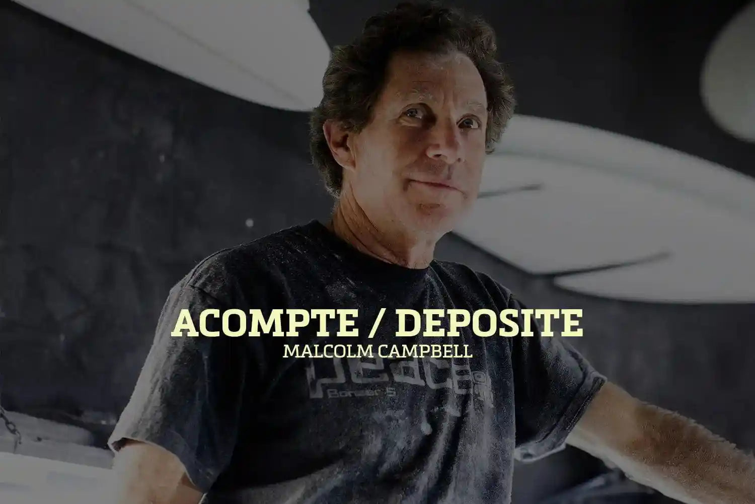 Shapers-Club- Dans une pièce faiblement éclairée, une personne en t-shirt sombre regarde la caméra. Les mots « Acompte deposite - Campbell Brothers » ressortent bien, évoquant l'héritage légendaire des frères Campbell. -surfshop-surfboard