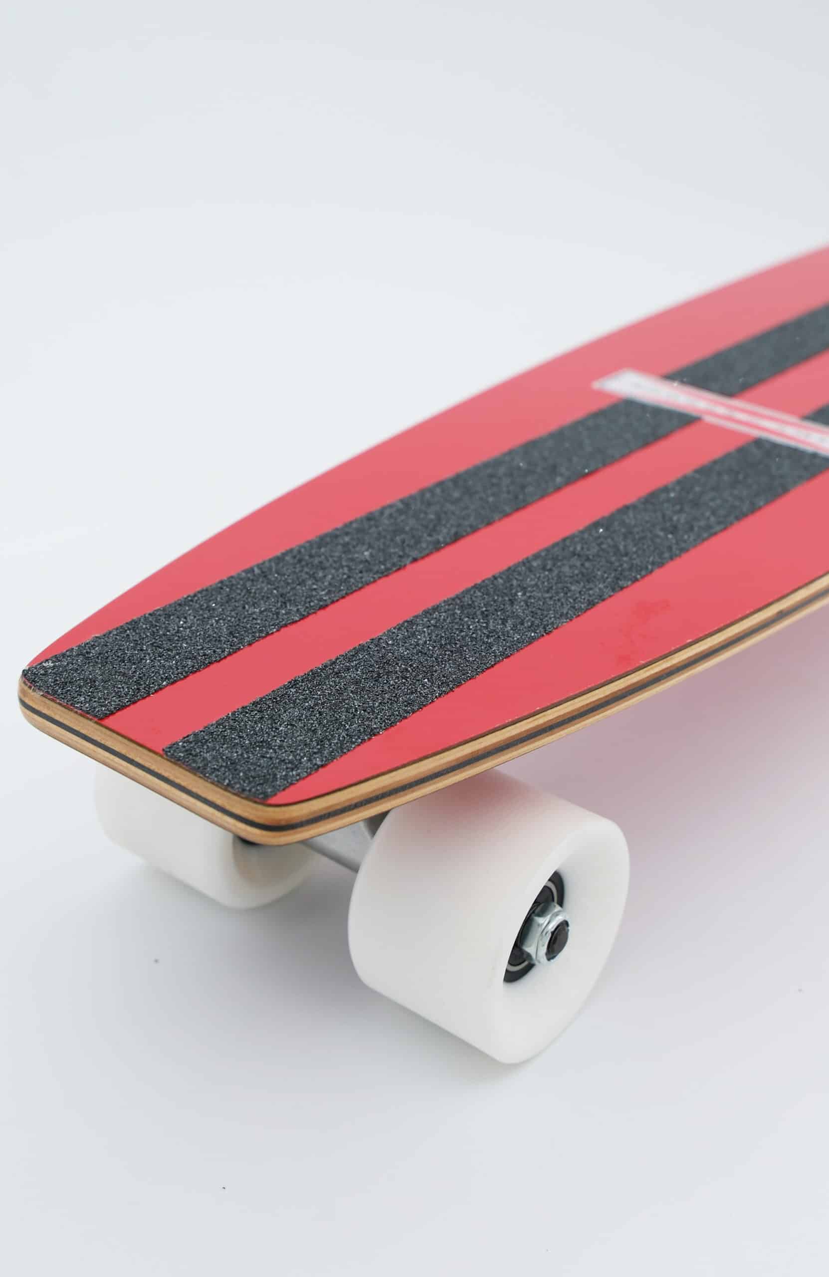 Shapers-Club- Un gros plan du SurfSkate Gordon & Smith 25" complet en Rouge Cerise présente ses bandes de grip noires, ses roues blanches et son bord en bois sur un fond blanc uni. -surfshop-surfboard
