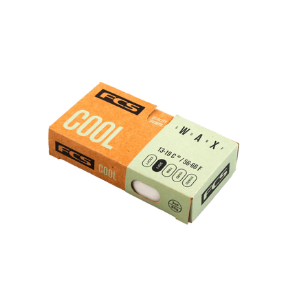 Shapers-Club- Une boîte en carton rectangulaire FCS contenant de la cire pour planche de surf étiquetée « FCS - Wax - Cool » pour des températures entre 13 et 19 °C (58 à 68 °F). La boîte est principalement marron et beige, avec du texte noir et blanc, et comprend une découpe circulaire qui révèle la cire blanche à l'intérieur. -surfshop-surfboard