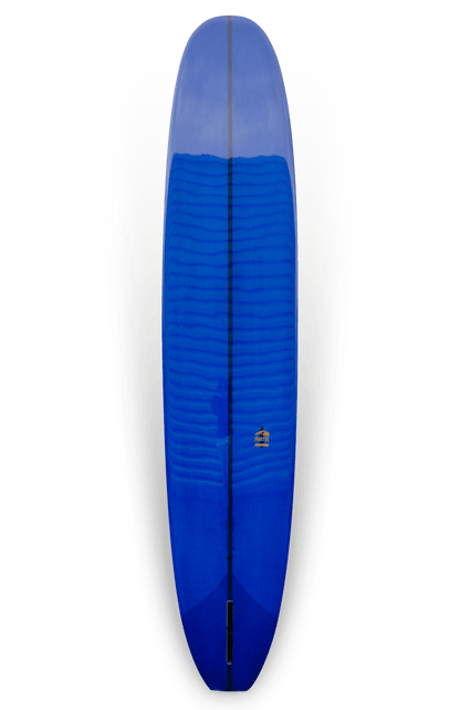 Shapers-Club- Une vue plongeante sur la planche de surf The Classic 9'6" x 23" x 3' 3/4" de Roger Hinds révèle une apparence lumineuse avec sa bordure blanche et jaune délavée sur les bords. La surface bleue présente une finition brillante, réfléchissant la lumière et affichant un petit emblème ou logo près du centre, révélateur du savoir-faire de Roger Hinds. -surfshop-surfboard