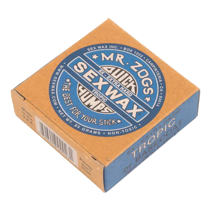 Shapers-Club- Une boîte marron et bleue de Sexwax - Tropic Basecoat de Mr. Zog, étiquetée « Quick Humps Tropic » et « The Best for Your Stick ». La boîte indique qu'elle est extra dure, non toxique et pèse 85 grammes. Idéal comme couche de base pour votre planche. -surfshop-surfboard