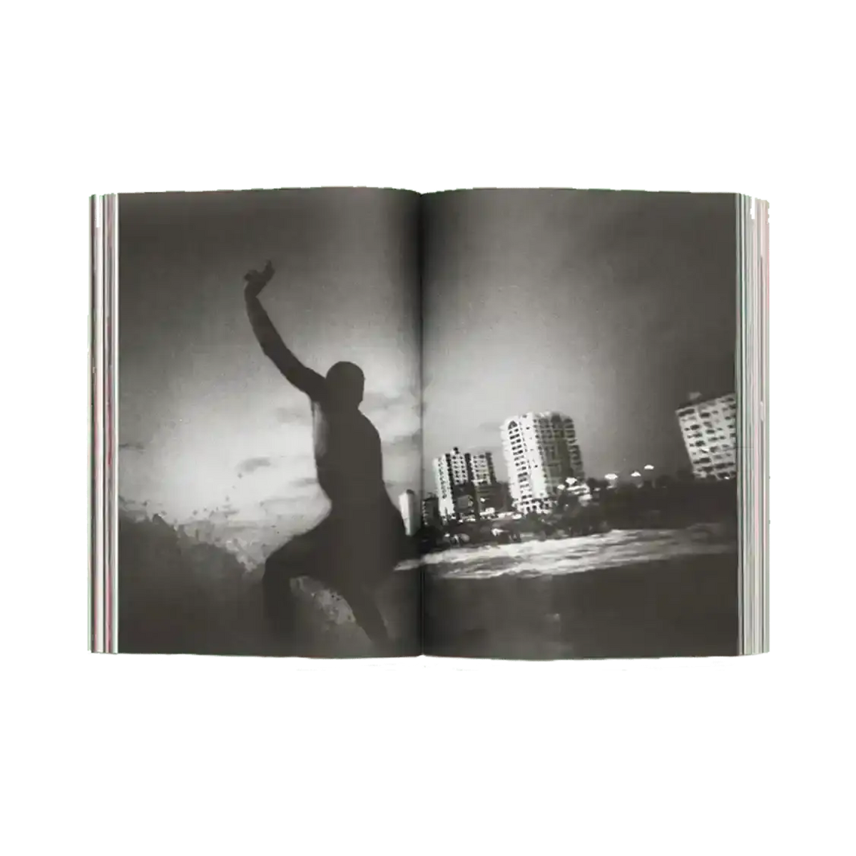 Shapers-Club- An open copy of ACID MAGAZINE - N°6 - WHATEVER SURFING MEANS presents a black and white surf photo: a surfer is surfing a wave near the city skyscrapers under a cloudy sky. -surfshop-surfboard