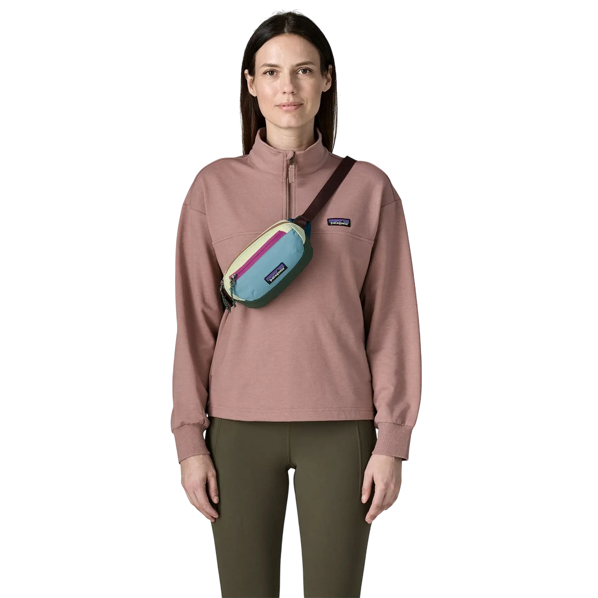Femme portant le sac banane Patagonia Terravia Mini Hip Pack multicolore en bandoulière sur un pull rose
