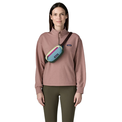 Femme portant le sac banane Patagonia Terravia Mini Hip Pack multicolore en bandoulière sur un pull rose